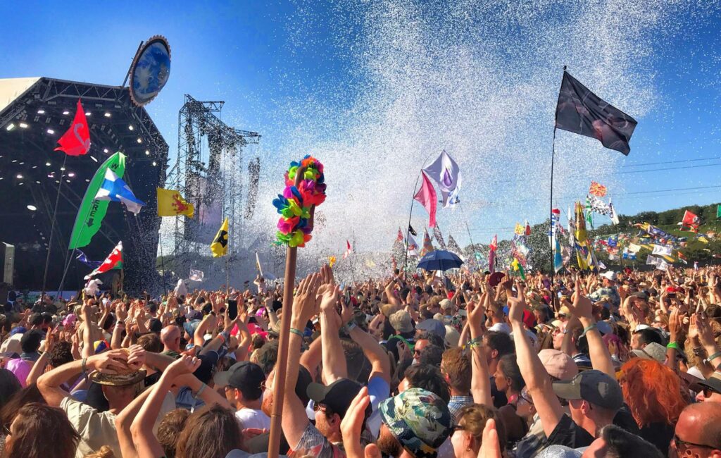 Fans in a live crowd put their hands in their air on a blue sky day