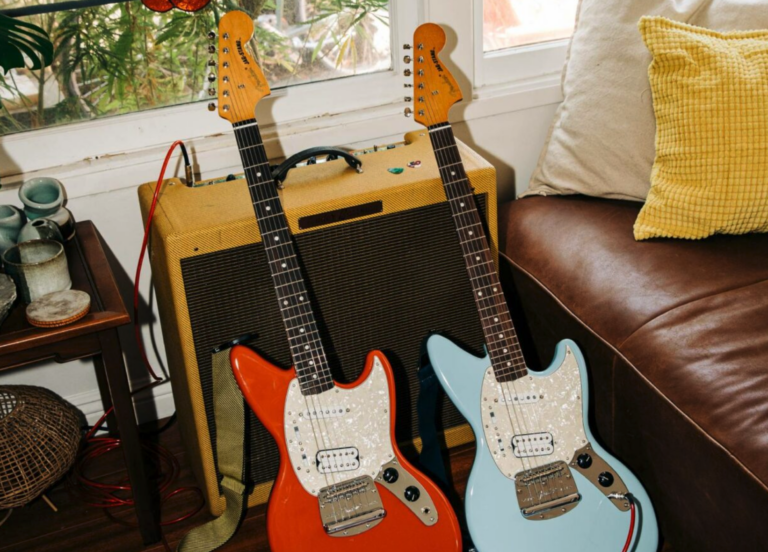 Two guitars leaning against an amp
