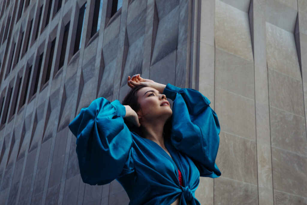 Mitski poses in a blue satin dress