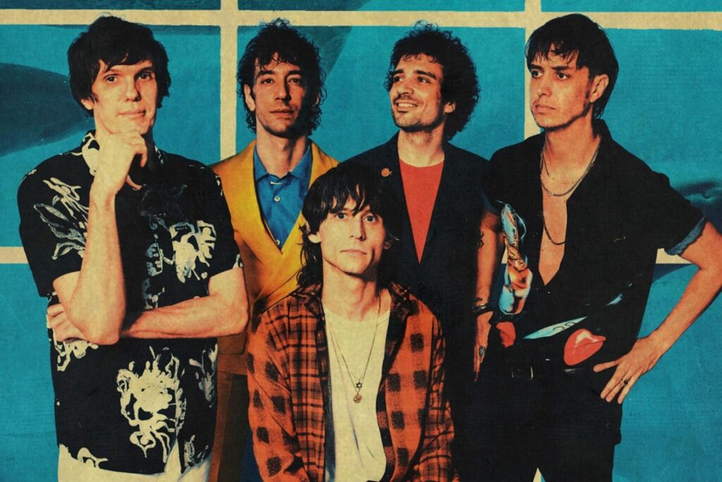 Photo showing the members of The Strokes who are standing in front of a blue tile background