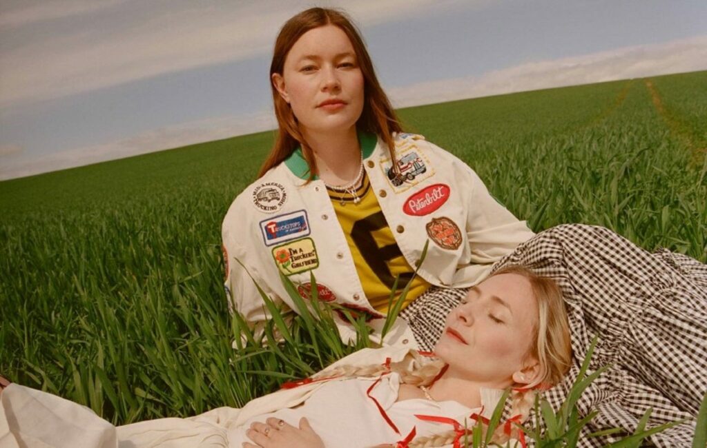 Wet Leg Press Shot of the duo sat in a field of grass