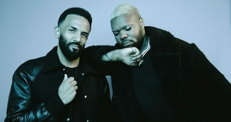 Craig David and MNEK pose for a photo, with MNEK leaning on Craig