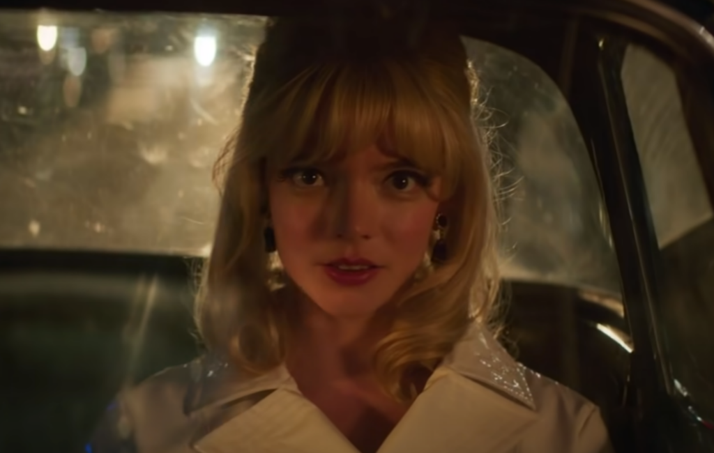Anya Taylor-Joy wears a white coat in the back of a car in 'Last Night In Soho'