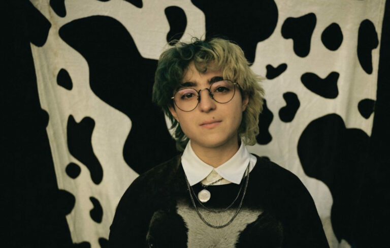 Claud looking at the camera in front of a cow print background