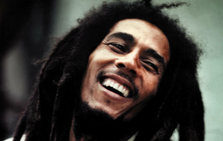 Bob Marley standing close to the camera, smiling with his head tilted to the left