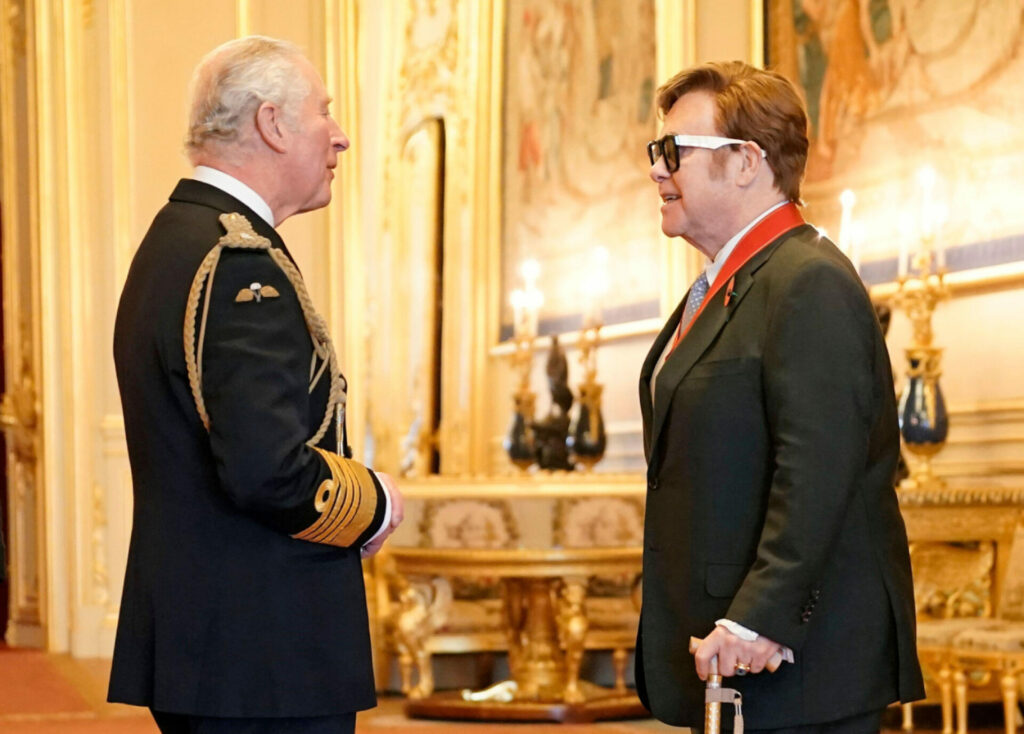 Elton John receives an award from Prince Charles.