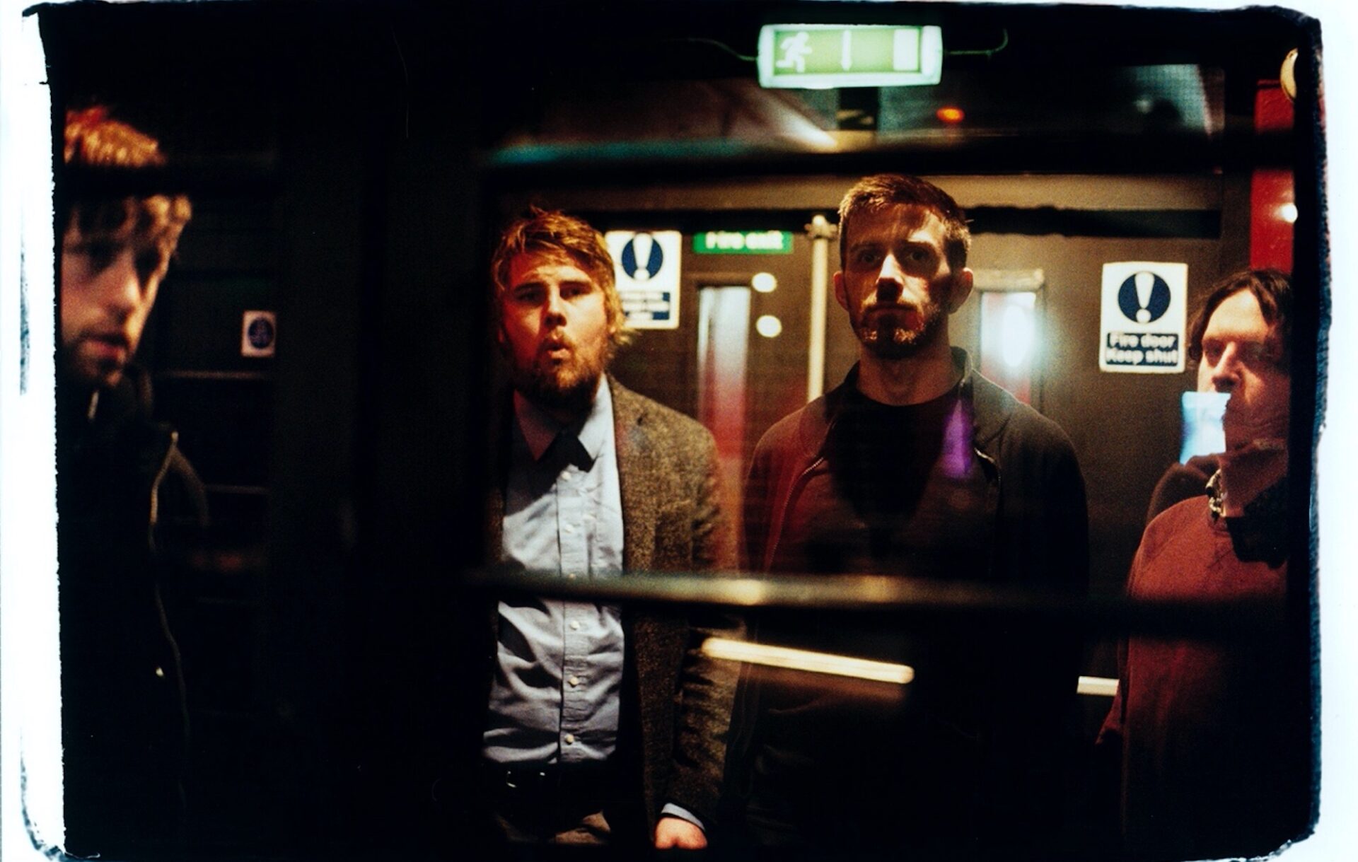 Gilla Band looking at the camera in a dark room
