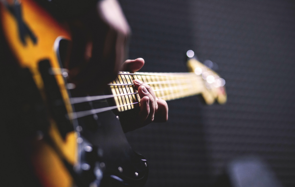 Side angle someone playing a bass guitar