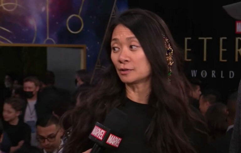 Chloé Zhao wears black and speaks into a Marvel microphone