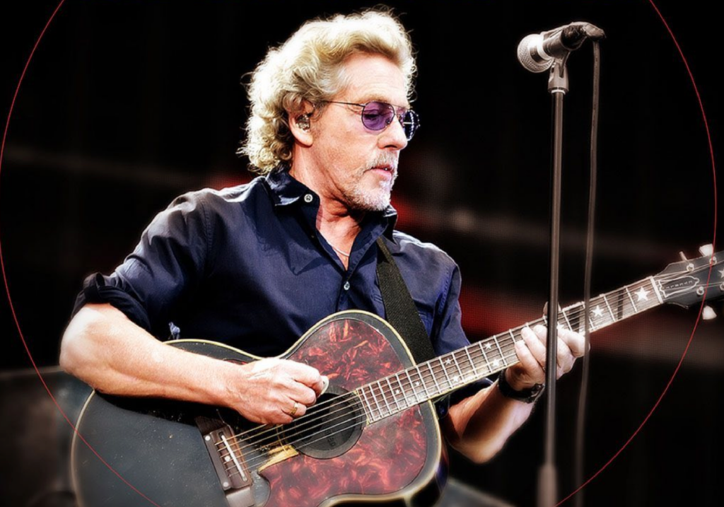 Roger Daltrey performs live in a blue shirt playing a guitar