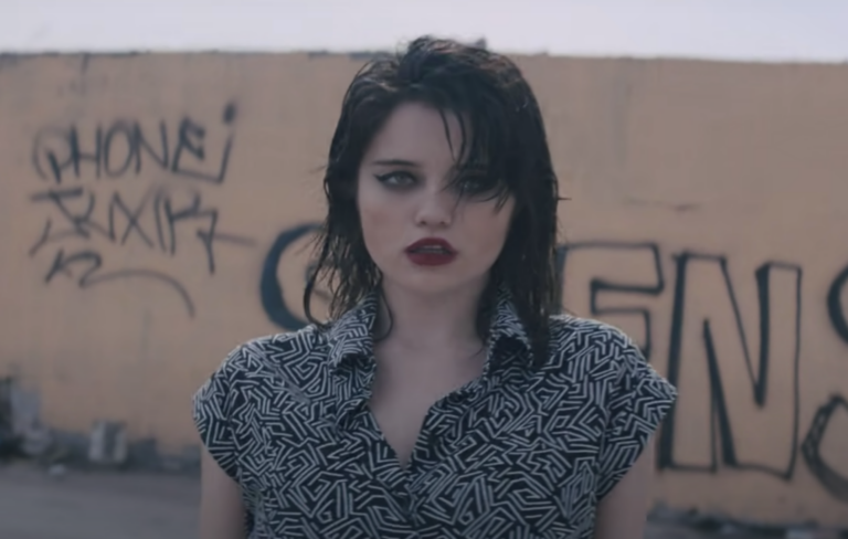 Sky Ferreira wears a white and black shirt and looks at the camera in the music video for 'I Blame Myself'