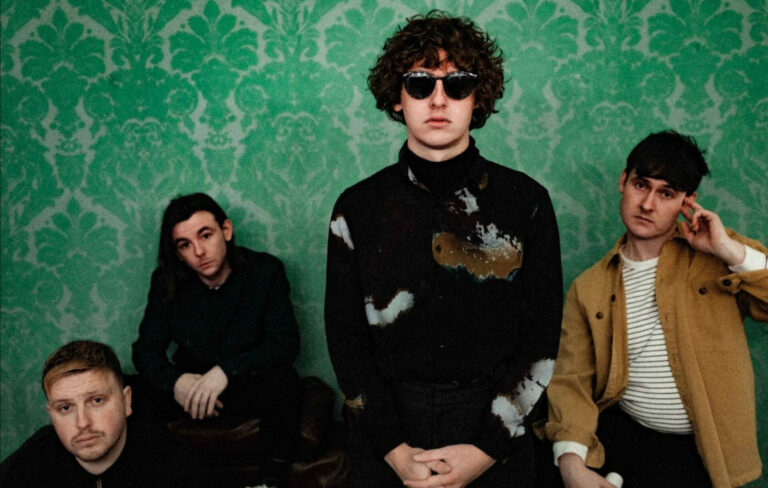 The Snuts pose against a green patterned wallpaper in a press photo