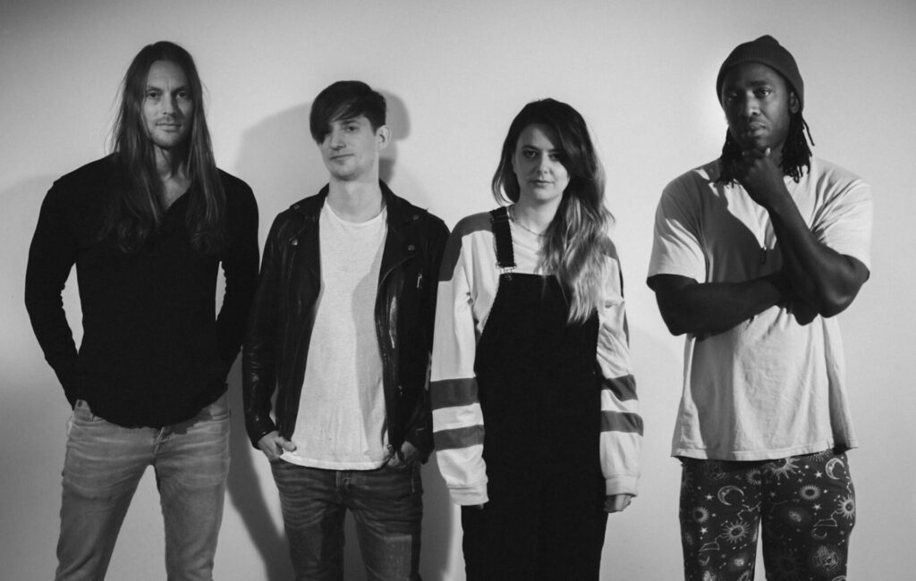 Black and white press photo of Bloc Party, standing in front of a white background.
