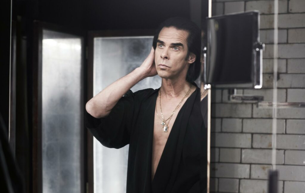 Nick Cave is seen posing in front of a mirror