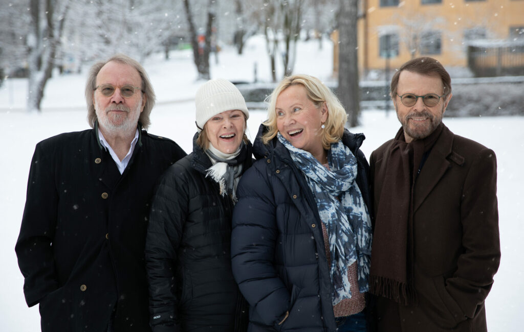 The members of ABBA pose in front of a snowy scene