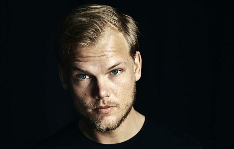 Avicii posing for the camera against a dark background