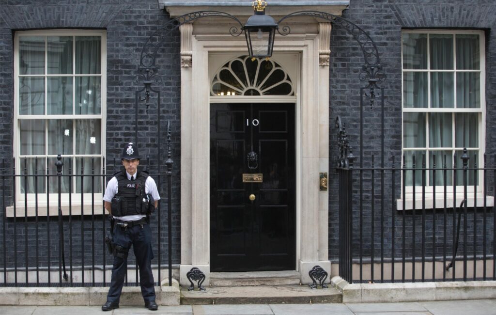 a police officer standing outside the front door of 10 Downing Street