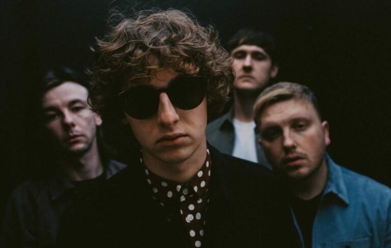 The Snuts pose for a press photo with their frontman wearing sunglasses