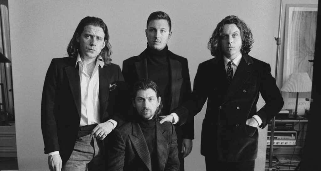 Arctic Monkeys pose for a press photo in black and white wearing suits/blazers and trousers