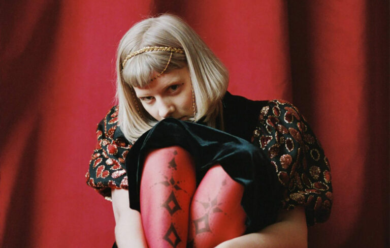 AURORA posing against a red backdrop