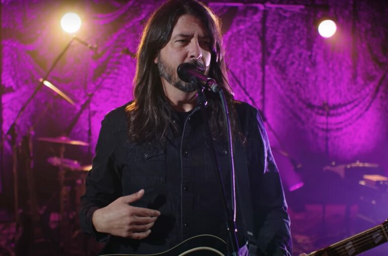 Dave Grohl performs live standing against a purple backdrop