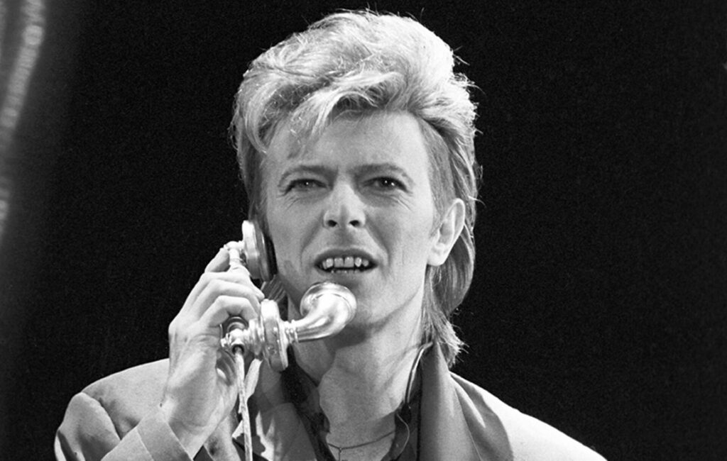 David Bowie holds a telephone up to his face in a black and white headshot photo