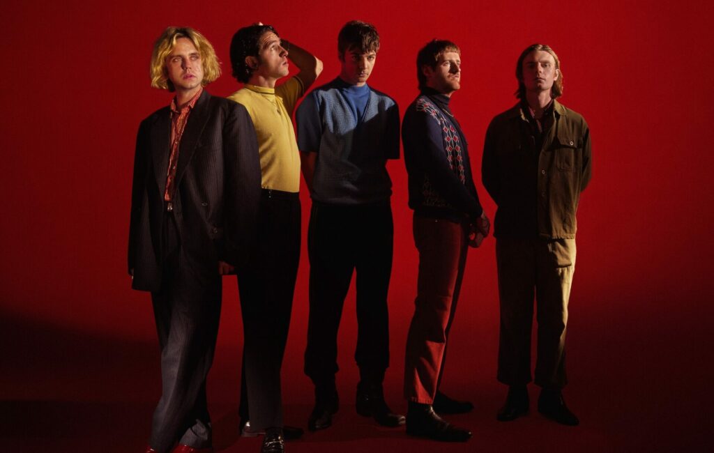 The five members of Fontaines D.C. pose in a line against a red background