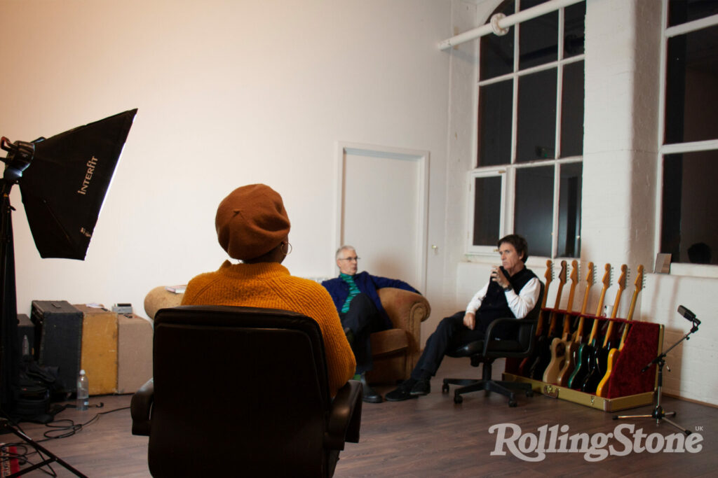 Johnny Marr and Jon Savage sit on a sofa and chair in a white room