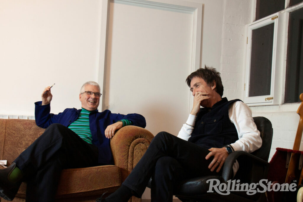 Jon Savage laughs on a sofa and Johnny Marr holds his hand to his face