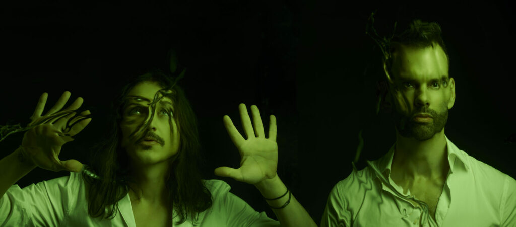 One member of Placebo puts their hands up in a dark, green tinged photo against a black background