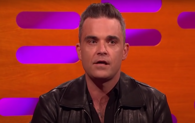 Robbie Williams wears a leather jacket on the Graham Norton Show sofa