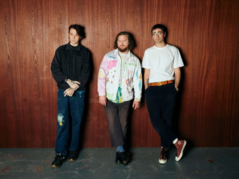 alt-J pose together against a wooden wall