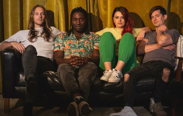 Members of Bloc Party sit on a sofa in a 2022 press shot