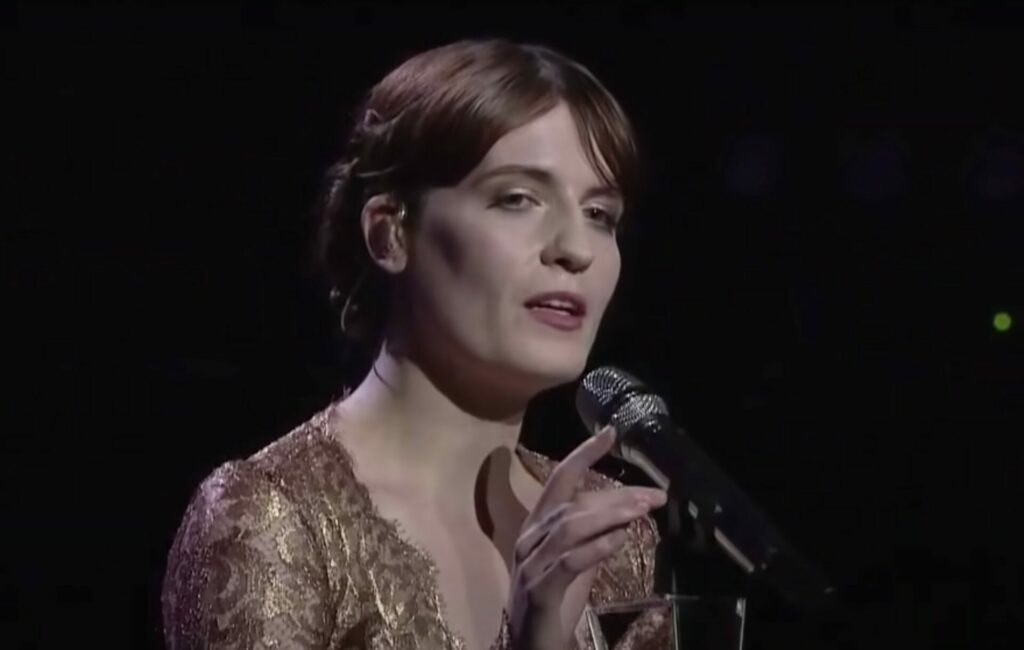 Florence Welch wears a gold dress and sings live
