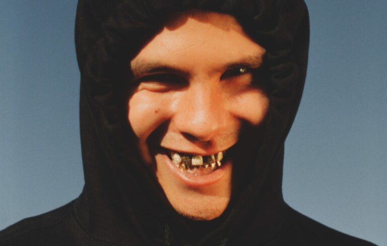slowthai smiling at the camera wearing a hoodie