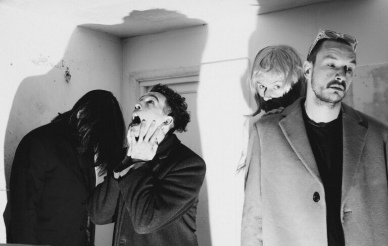 The members of The 1975 pose inside a house in a black-and-white photograph