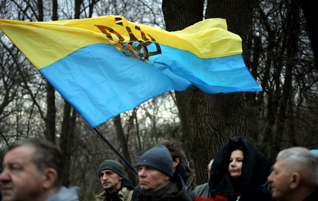 A Ukrainian flag with the tryzub (trident) flies above the people attending the commemorative event for the Debalt
