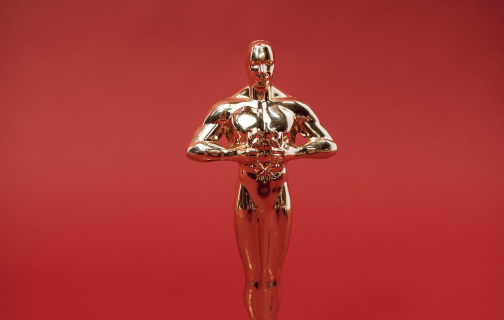 An Oscar trophy in front of a red background