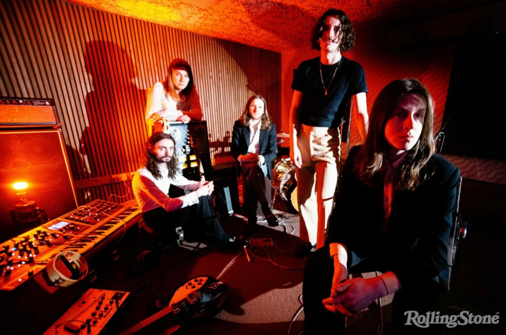 Blossoms pose as a group in a studio under a red tinged light