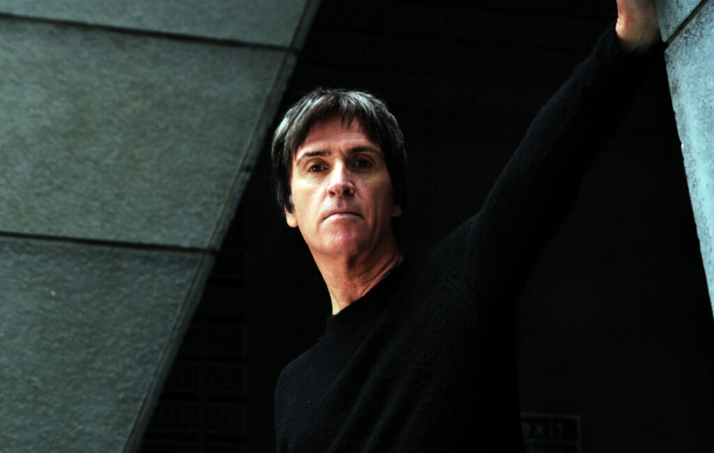 Johnny Marr poses for a press photo in a black jumper