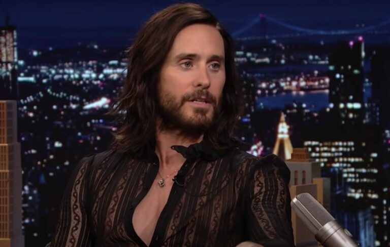 Jared Leto wears a low button up shirt on the Jimmy Fallon couch