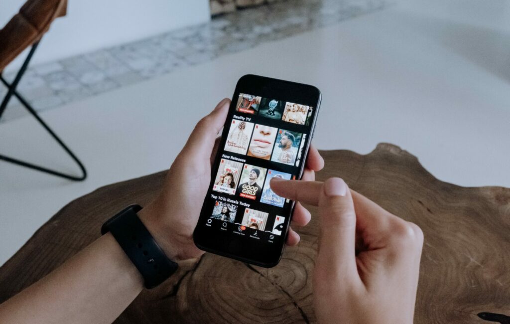 A hand holds a phone with the Netflix app open