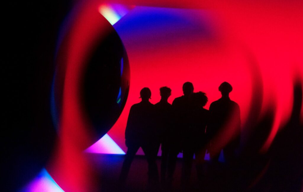The members of Arcade Fire pose in silhouette for a press photo