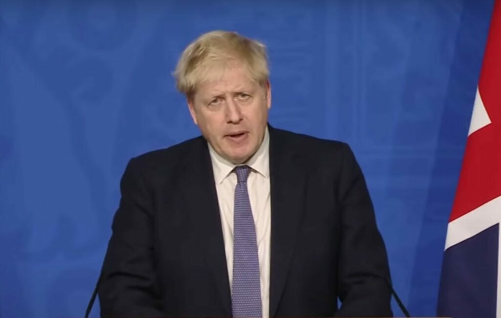 Boris Johnson gives a press conference against a blue background
