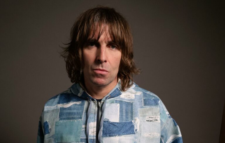 Liam Gallagher poses in a denin patchwork jacket