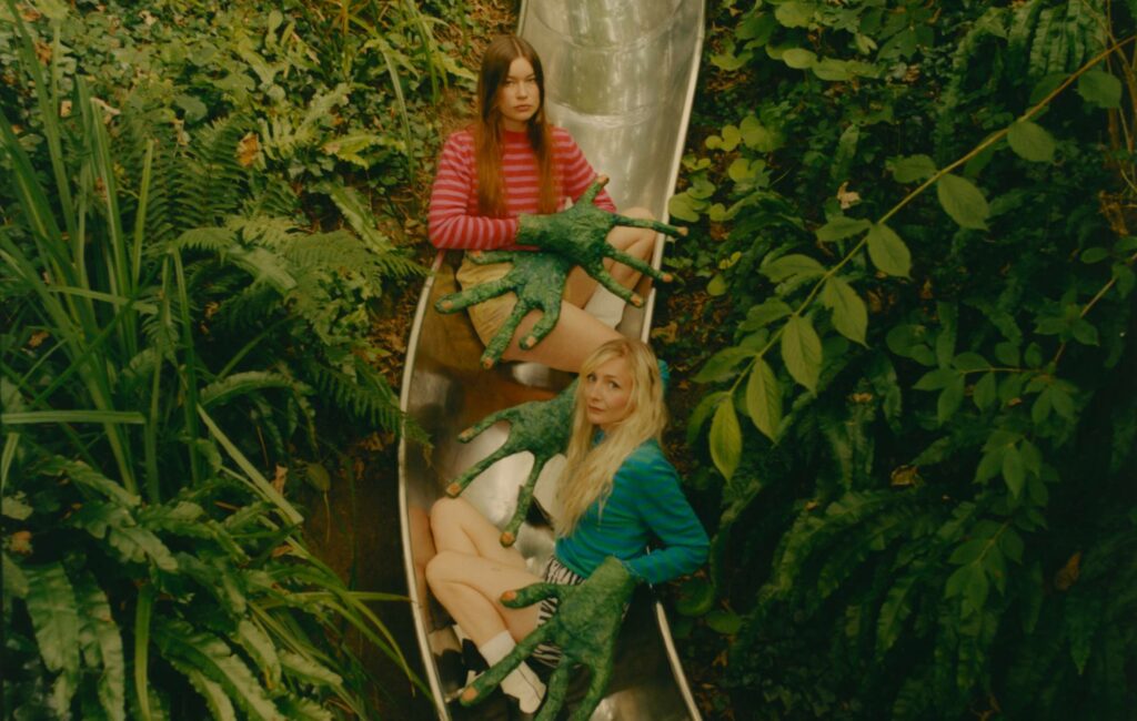 Wet Leg posing on a metal slide in a forest