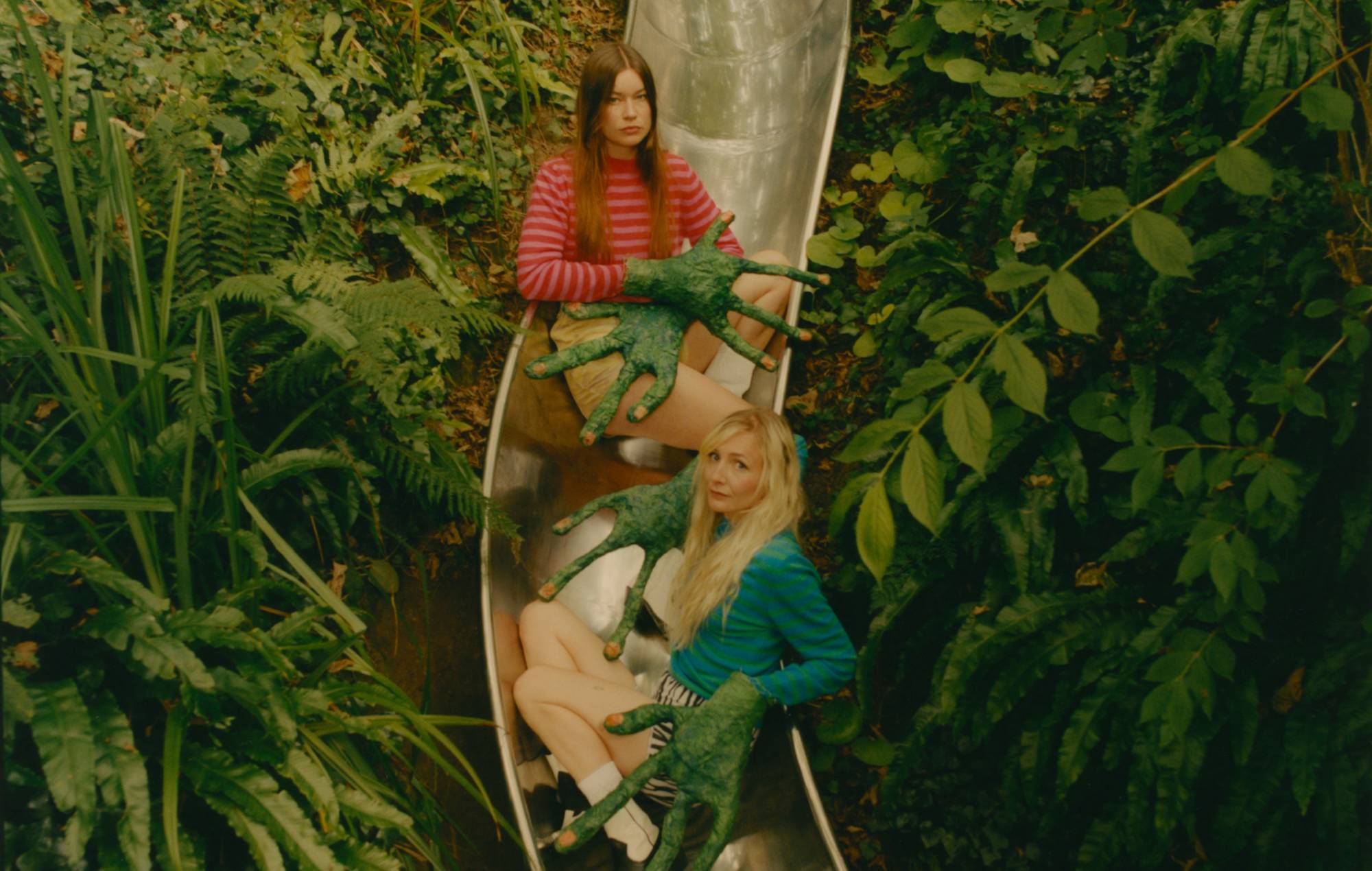 Wet Leg posing on a metal slide in a forest