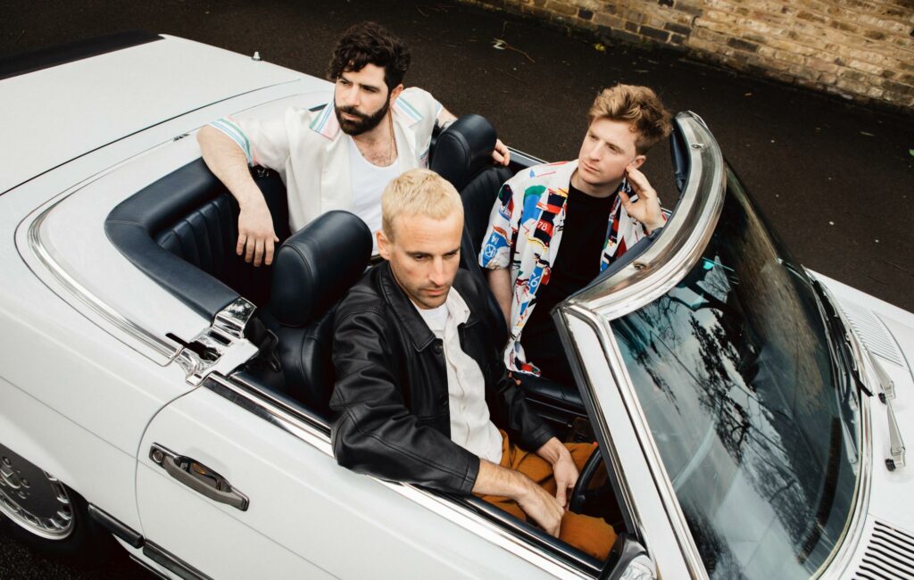 Members of Foals are seen posing in a white convertible car