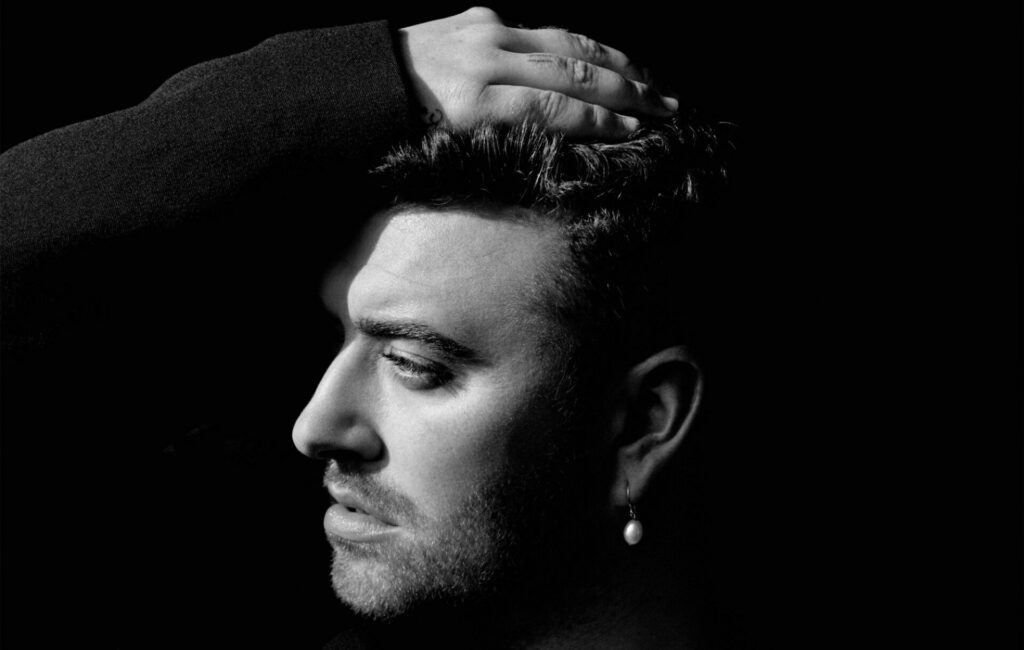 Sam Smith poses in a side angle with his hand on his head in a black and white photo
