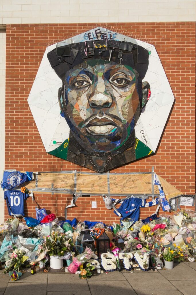 A painted mural of Jamal Edwards with flowers placed in front of it